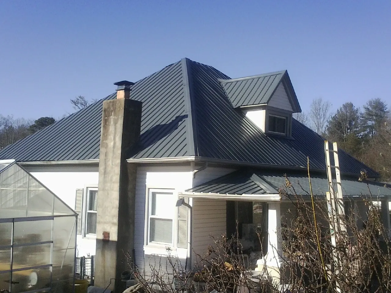 Dark blue standing seam metal roof on a white farmhouse with dormer — Slate & Tile Roof Repair by Roofing Brothers in Millerton