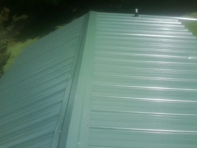 New green metal panels meeting at the ridge of a roof — Flat Roof Repair work by our crew in Millerton