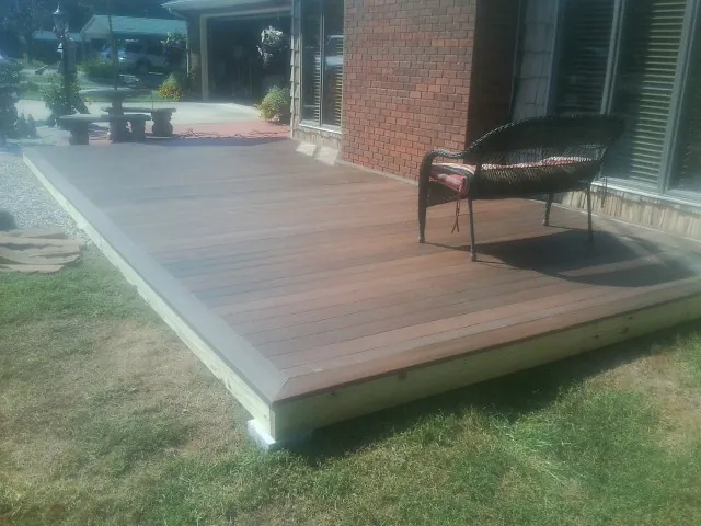 New wood deck and wicker chair beside a brick house in Millerton