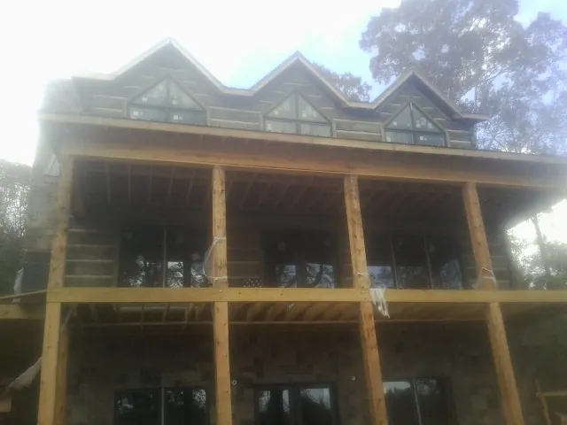 Dormers and porch framing on a large log home under construction — Roof Coating work by our crew in Millerton