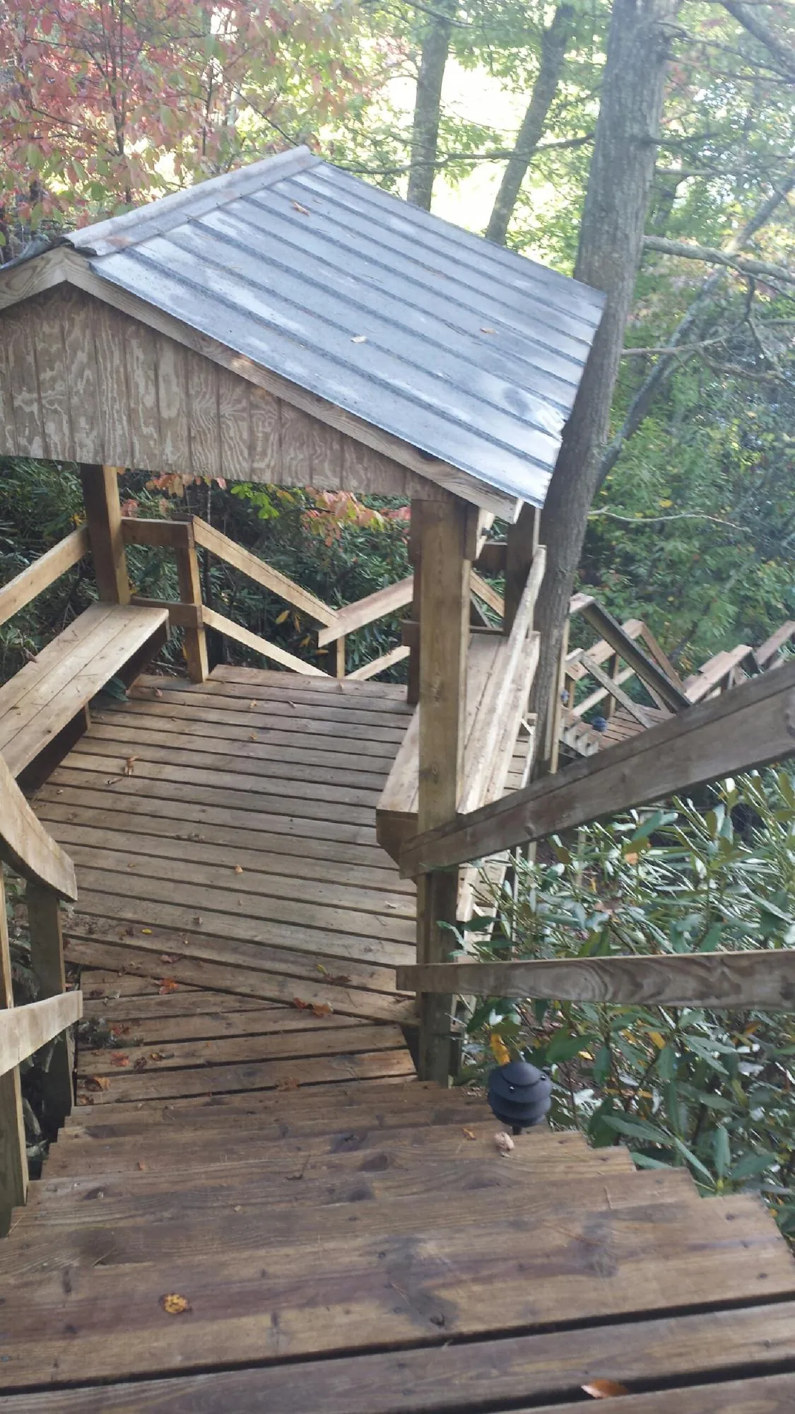 Metal roofed shelter over wooden steps on a wooded walkway — Skylight Repair & Installation work by our crew in Millerton