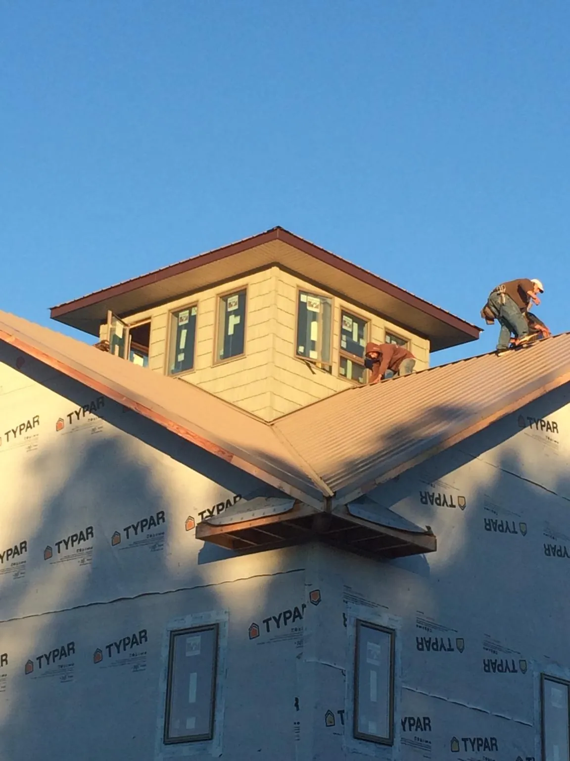 Roofers working around a rooftop cupola on a new metal roof at sunset — Roof Waterproofing in Millerton by Roofing Brothers